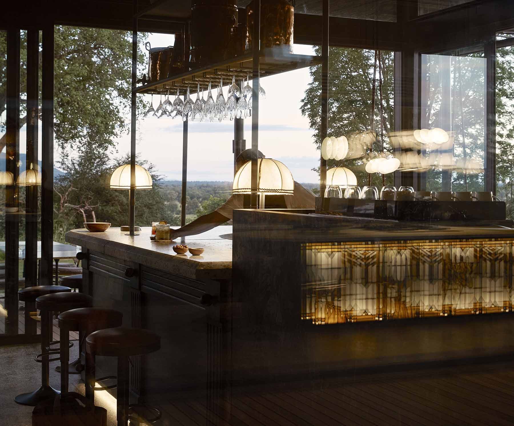 The bar at Chichele at sundown, lamps lit and the valley beyond the glass