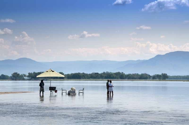 Guests wading the shallows of the Zambezi at Lolebezi